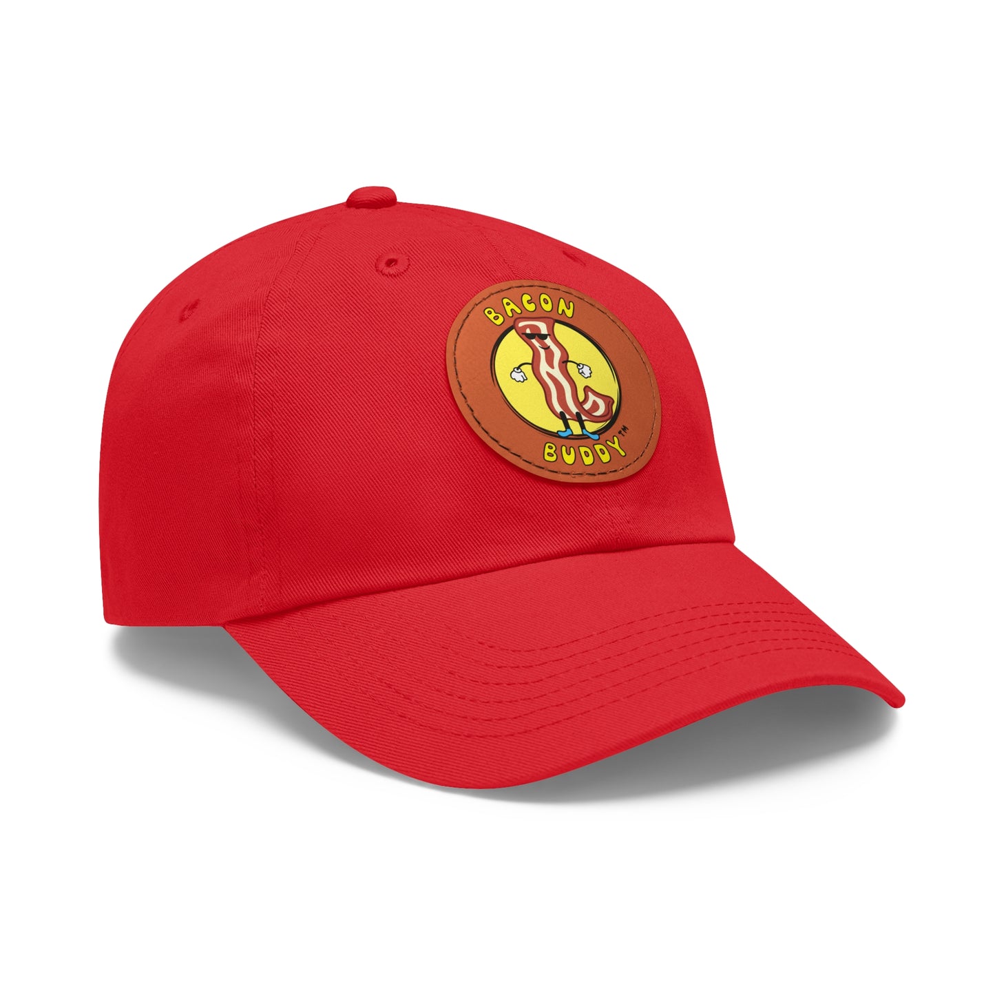 'Dad hat' style Red coloured baseball cap with a round, brown leather patch sewn on the front. Printed on the leather patch is a yellow circular graphic logo of the Bacon Buddy character, a cartoon style strip of bacon with arms, legs and sunglasses. Curved yellow text of Bacon Buddy around the logo. Photographed is front / side view 